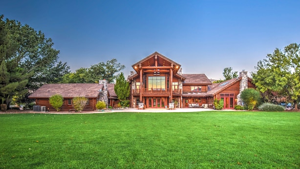 A large, two-story log cabin with a spacious front yard and a well-maintained lawn.