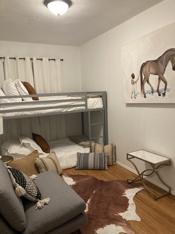 A bunk bed room with a cowhide rug, pillows, a small table, and a painting of a horse. - Ranch Style Home in the Heart of Wine Country with E-bikes! (Solvang)
