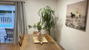 Un coin repas avec une table en bois, des chaises, un banc, une plante en pot et un tableau accroché au mur.