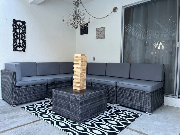 A sectional sofa, a wooden block tower, and a patterned rug in a modern outdoor seating area. - Ranch Style Home in the Heart of Wine Country with E-bikes! (Solvang)