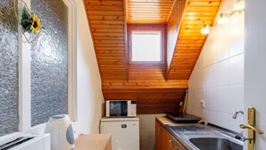 A compact kitchen with wooden cabinets, a microwave, a toaster, and a sink.