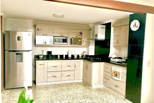 A kitchen with a refrigerator, microwave, stove, and cabinets.
