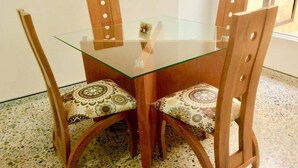 Een eettafel met glazen blad en vier houten stoelen, elk voorzien van gestreepte kussens.