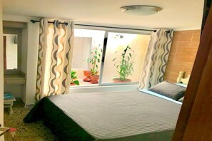 A bedroom with a bed, a window with curtains, a potted plant, and a view of the outside. - Beautiful Home / No stairs / short walk to public transit (Envigado)
