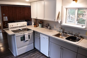 A compact kitchen with white cabinetry, a built-in stove, and a dishwasher. - Lakeside fun in the North Woods (Spooner)