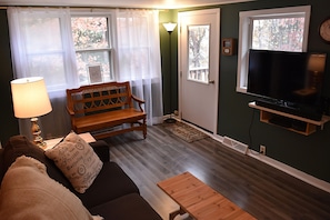 Relax in this inviting living space with a comfortable sofa, wooden bench, and flat-screen TV.