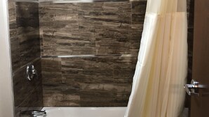 A bathroom with a bathtub, a shower curtain, and tiled walls.
