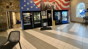 A public space with vending machines, a statue, and a stone wall.