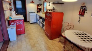 Een kleine keuken met een koelkast, gootsteen en een eethoek.