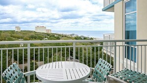 A balcony with a table and chairs, overlooking a coastal view with buildings in the distance. - 1BR Horizons Condo On Beautiful Myrtle Beach Resort w/Amenities (Myrtle Beach)