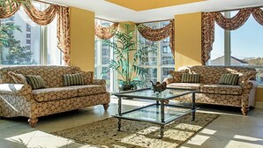 A living room with two patterned sofas, a glass coffee table, and large windows with curtains. - 1BR Horizons Condo On Beautiful Myrtle Beach Resort w/Amenities (Myrtle Beach)