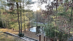 A wooden deck leading to a pond surrounded by trees.