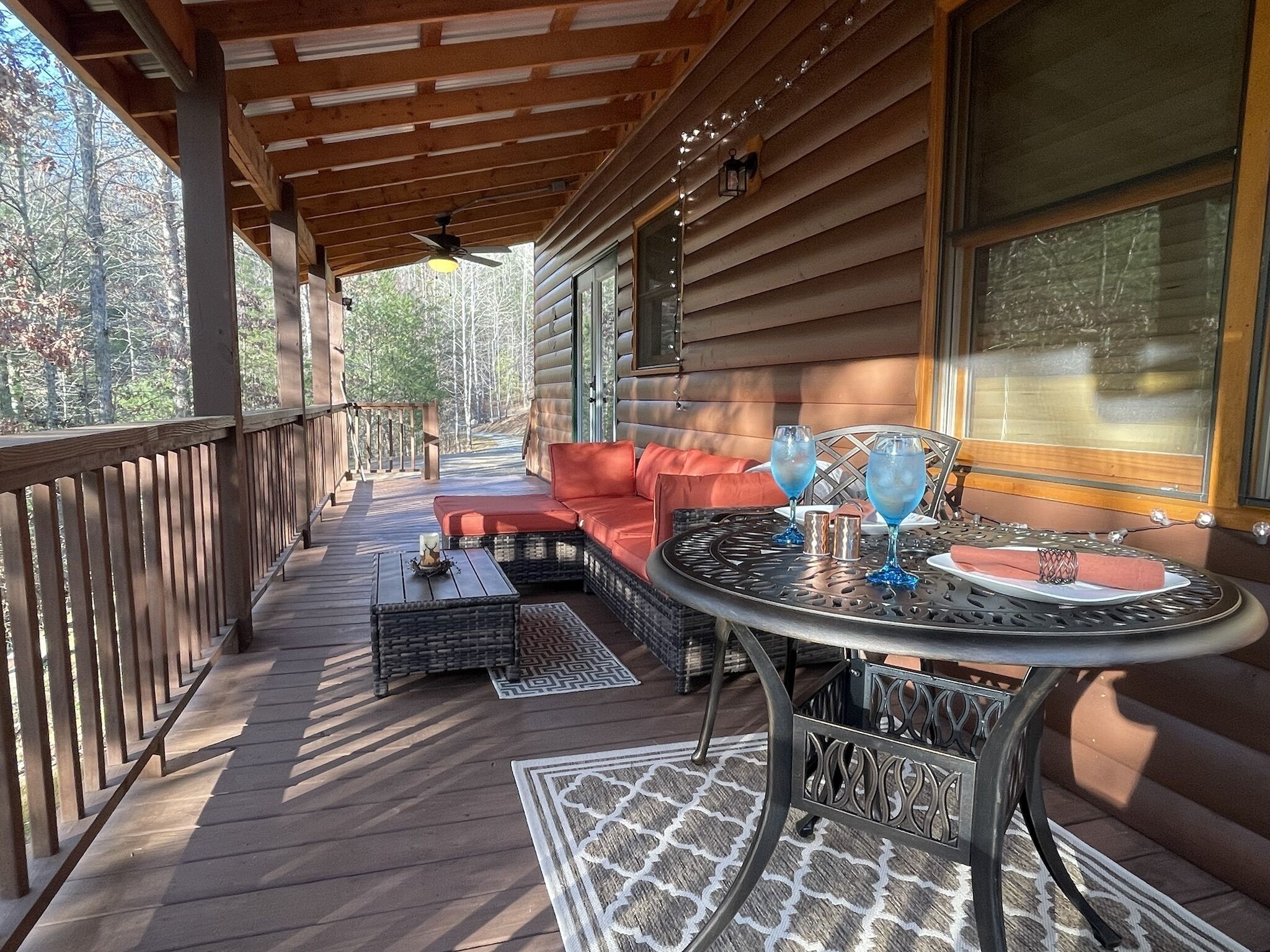 A covered outdoor seating area with a sofa, a round table, and two chairs.