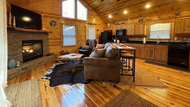 A spacious living room with a fireplace, a leather couch, and a dining area.