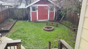 Enjoy a peaceful retreat in this serene backyard with a fire pit, wooden bench, and lush garden.