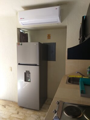 Een magnetron, kookgerei, borden en bestek, keukeneiland