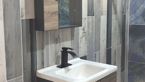 A modern bathroom with a large mirror, a black faucet, and a wooden vanity.