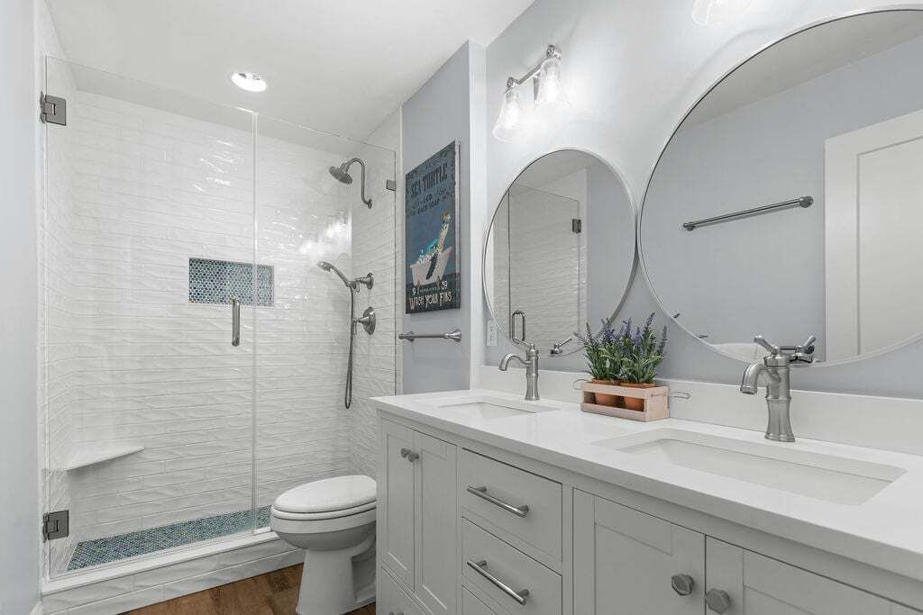Une salle de bain moderne équipée d’une douche, de toilettes, d’un meuble-lavabo et d’un grand miroir.