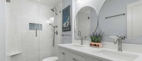 Une salle de bain moderne équipée d’une douche, de toilettes, d’un meuble-lavabo et d’un grand miroir.
