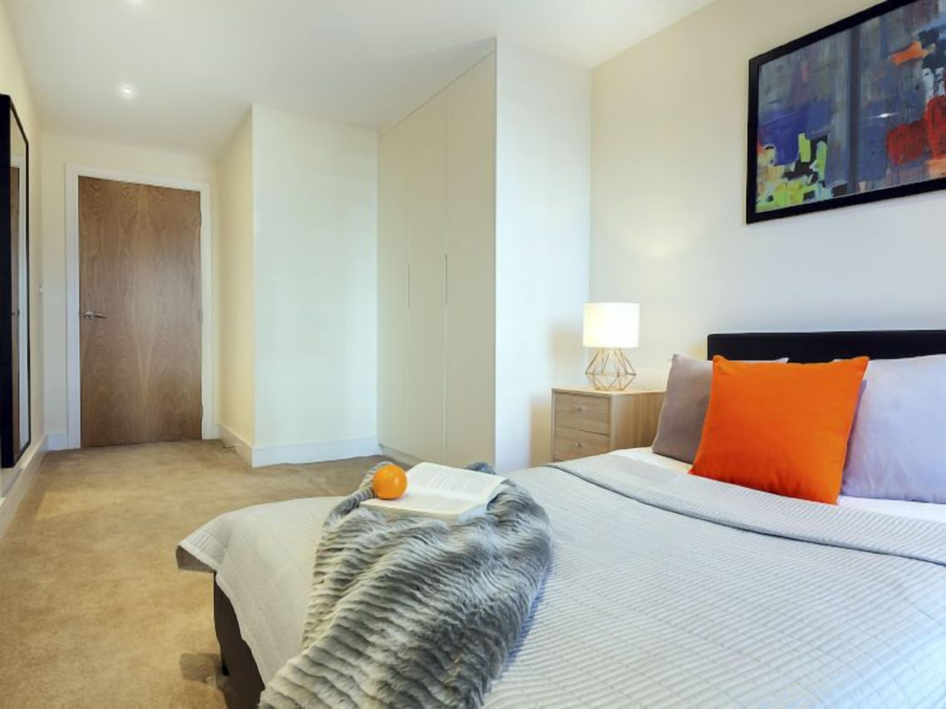 Una camera d'albergo con un letto, un comodino, una lampada e un quadro appeso al muro.