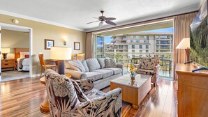 A spacious living room with a sofa, chairs, a coffee table, and a ceiling fan.