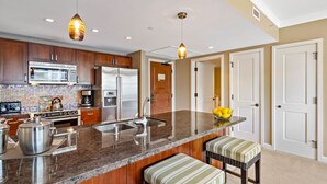A modern kitchen with granite countertops, stainless steel appliances, and a central island with bar stools.
