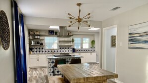 A kitchen with a wooden table and bench, a ceiling fan, and a backsplash with star patterns. - Games Galore & Rooftop Deck by St. Mary's, BMT (San Antonio)