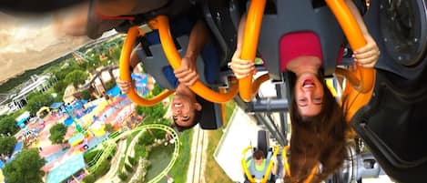 A view from a roller coaster, including the track and surrounding amusement park area.