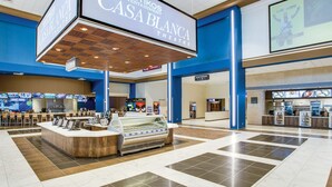 A spacious atrium with a central ice cream display, a digital screen advertising CASA BLANCA theatre, and a seating area with a blue and beige color scheme. - Games Galore & Rooftop Deck by St. Mary's, BMT (San Antonio)