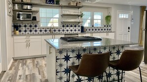 A modern kitchen with a large island, white cabinets, and a star-patterned backsplash. - Games Galore & Rooftop Deck by St. Mary's, BMT (San Antonio)
