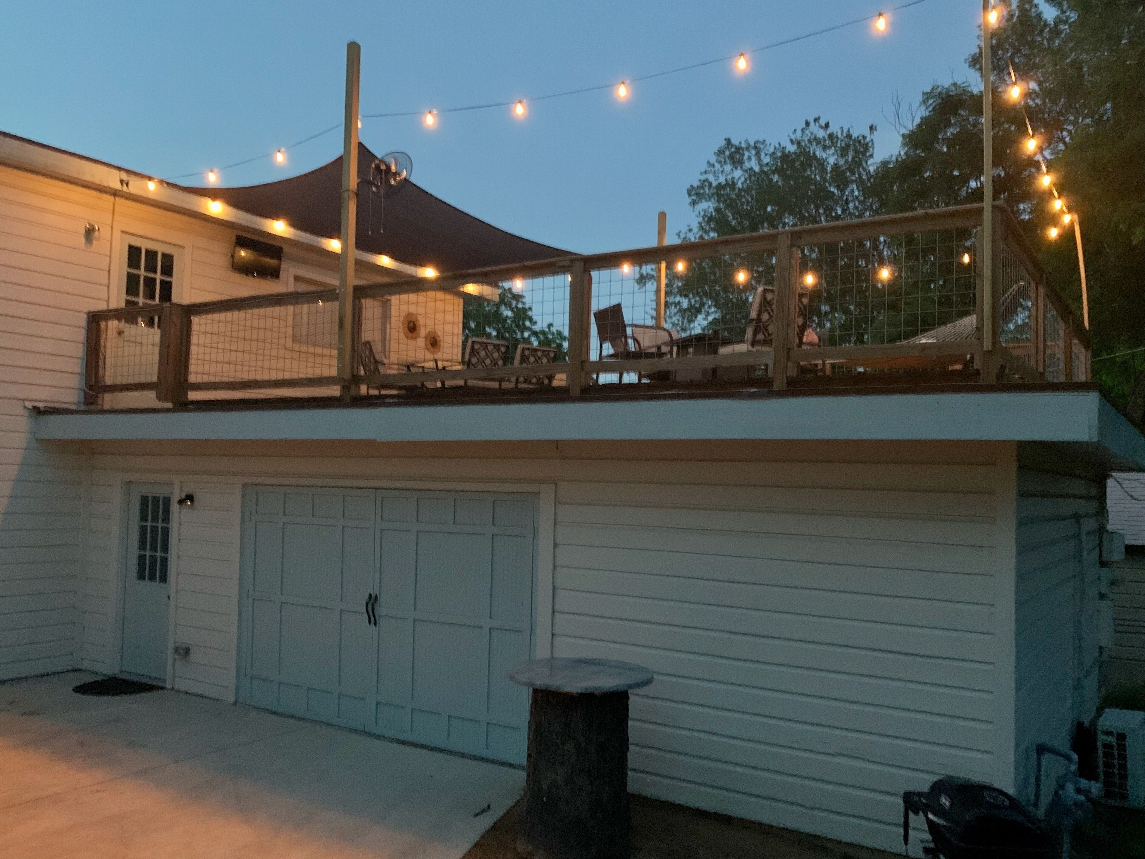 Ein zweistöckiges Gebäude mit überdachter Terrasse, Garage und Lichterketten.