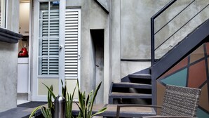 An outdoor patio area with a table and chairs, a staircase, and a door leading to a kitchen. - Deluxe Room in Condesa + Rooftop & Coworking - Beta by Nomadier (Ciudad de México)