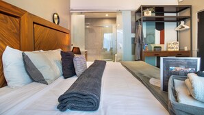 A hotel room with a large bed, a wooden headboard, a bedside table with a lamp, a mirror, and a view of the bathroom. - Deluxe Room in Condesa + Rooftop & Coworking - Beta by Nomadier (Ciudad de México)