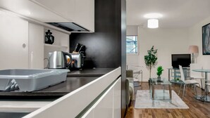 Una cucina moderna con uno schienale nero, elettrodomestici in acciaio inossidabile e un'area pranzo con un tavolo in vetro e sedie.