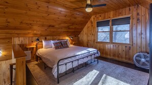 A wooden cabin bedroom with a bed, a ceiling fan, a window, and a fan on the floor. - Owens Perch - pet friendly, big views near downtown Boone (Boone)