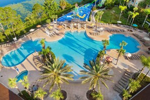 Un área de piscina en un complejo turístico con múltiples piscinas, tumbonas y palmeras.
