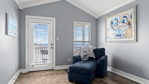 A room with grey walls, a blue armchair, and a large abstract painting.