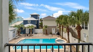 A backyard with a swimming pool, palm trees, and a small deck.