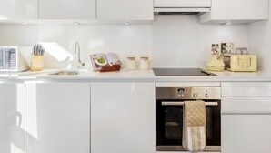 Una cocina moderna con armarios blancos, un horno de acero inoxidable y un tostador.