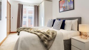 Un dormitorio moderno con una cama grande, una mesita de noche y un cuadro en la pared.