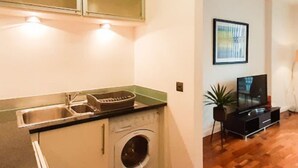 Una cocina compacta con lavadora integrada, un lavamanos y un microondas.