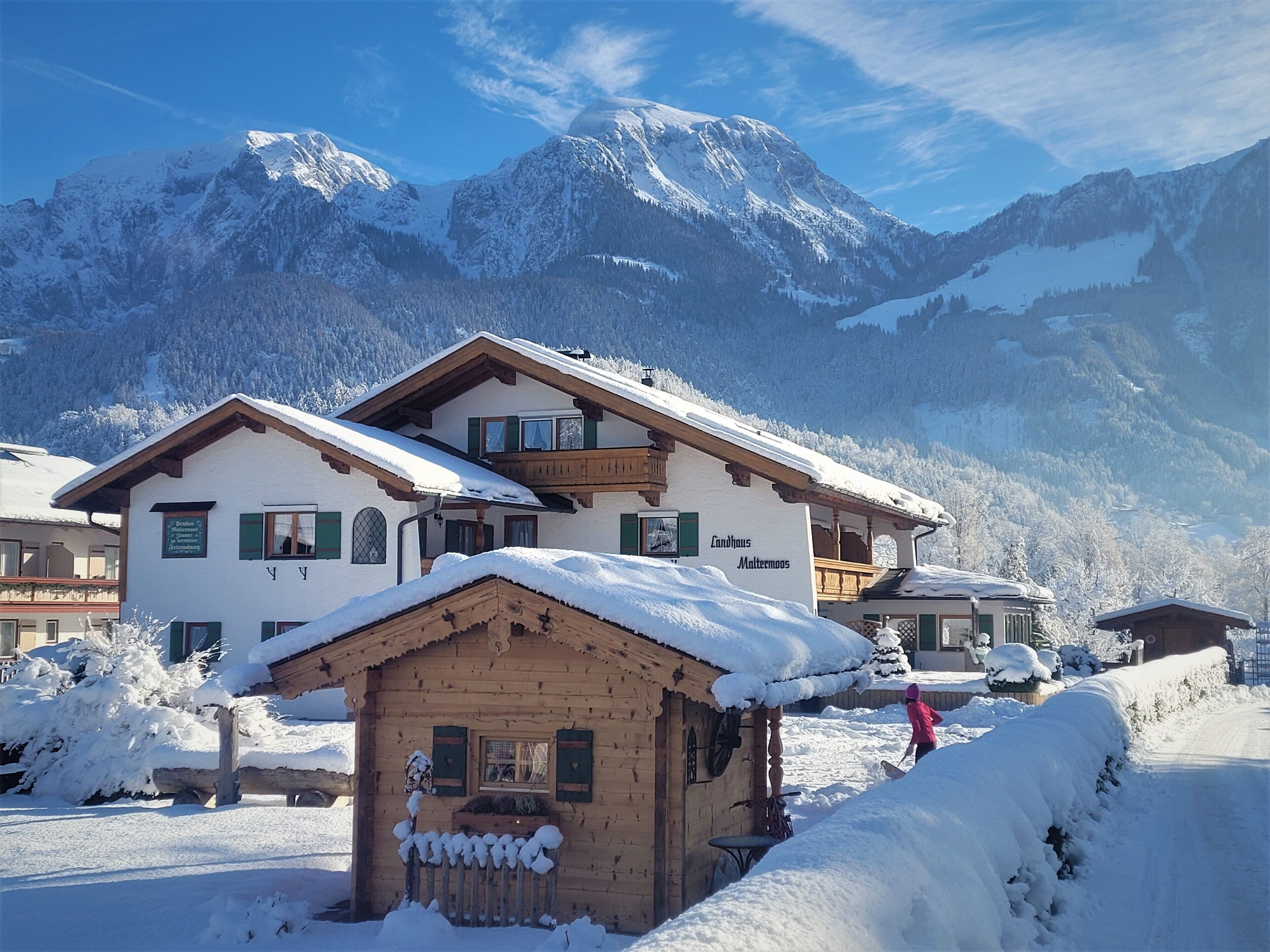 Een klassiek chalet in Alpenstijl met een houten gevel, een balkon en een bordje dat het als gastenverblijf identificeert.