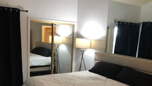 Quarto com cama, espelho, abajur e guarda-roupa.