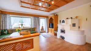 A cozy living room with a wooden ceiling, a fireplace, and a TV. - Fewo , Balkon, Kochnische, 2 Schlaf- und 1 Wohn-/schlafzimmer, max 5 Personen (Ruhpolding)