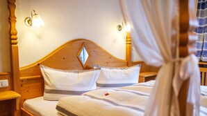 A double bed with a wooden headboard, two bedside tables, and a canopy. - Fewo , Balkon, Kochnische, 2 Schlaf- und 1 Wohn-/schlafzimmer, max 5 Personen (Ruhpolding)