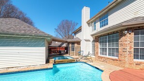 A residential swimming pool with a wooden deck, a brick wall, and a covered patio area. - Relax in our spacious villa, just a quick ride away to Grapevine Malls & Airport (Highland Village)