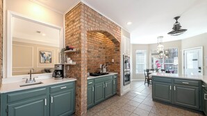 A kitchen with teal cabinets, a brick accent wall, and a central island. - Relax in our spacious villa, just a quick ride away to Grapevine Malls & Airport (Highland Village)