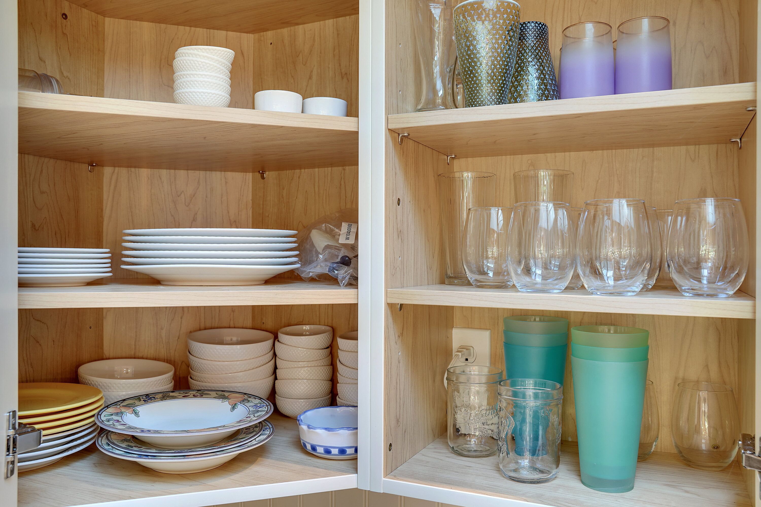 A wooden cabinet with shelves holding various glassware and dishes.