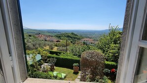 Vista desde una ventana con un paisaje rural que incluye casas, vegetación y un cielo despejado.
