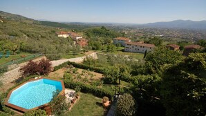 Zona residencial con piscina, rodeada de vegetación y casas con techos de tejas rojas.